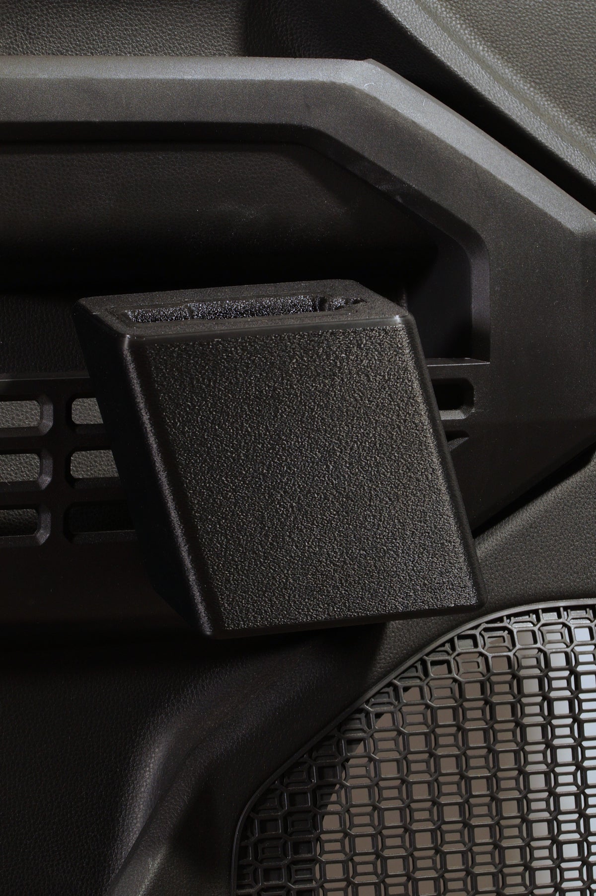 A close-up of a black textured plastic handgun holster attached to a dark gray vehicle door panel for a Toyota.