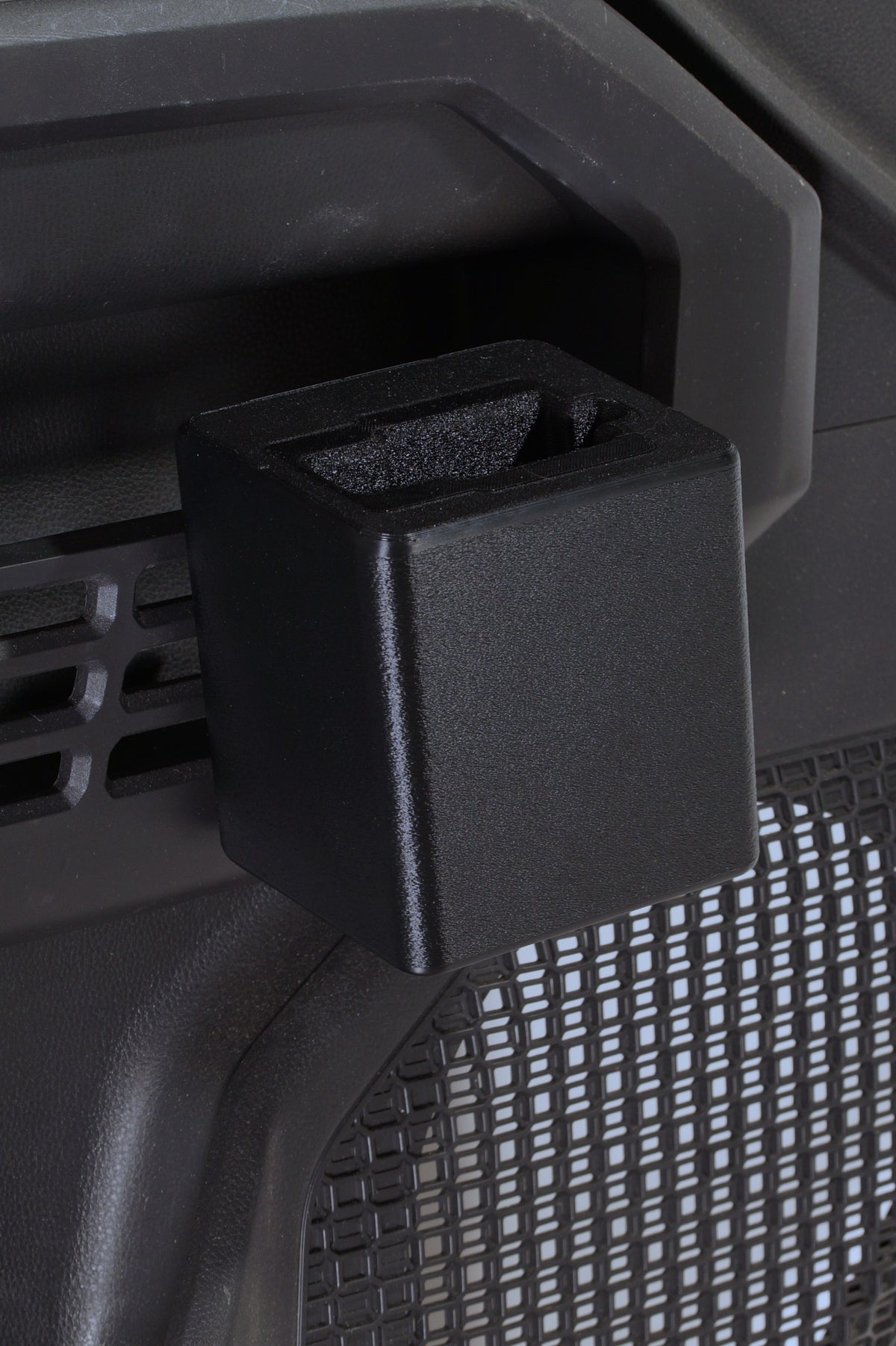 Close-up of a black plastic furniture accessory, likely a leg guard or protective cap, attached to the side of a dark gray office chair with a mesh seat.