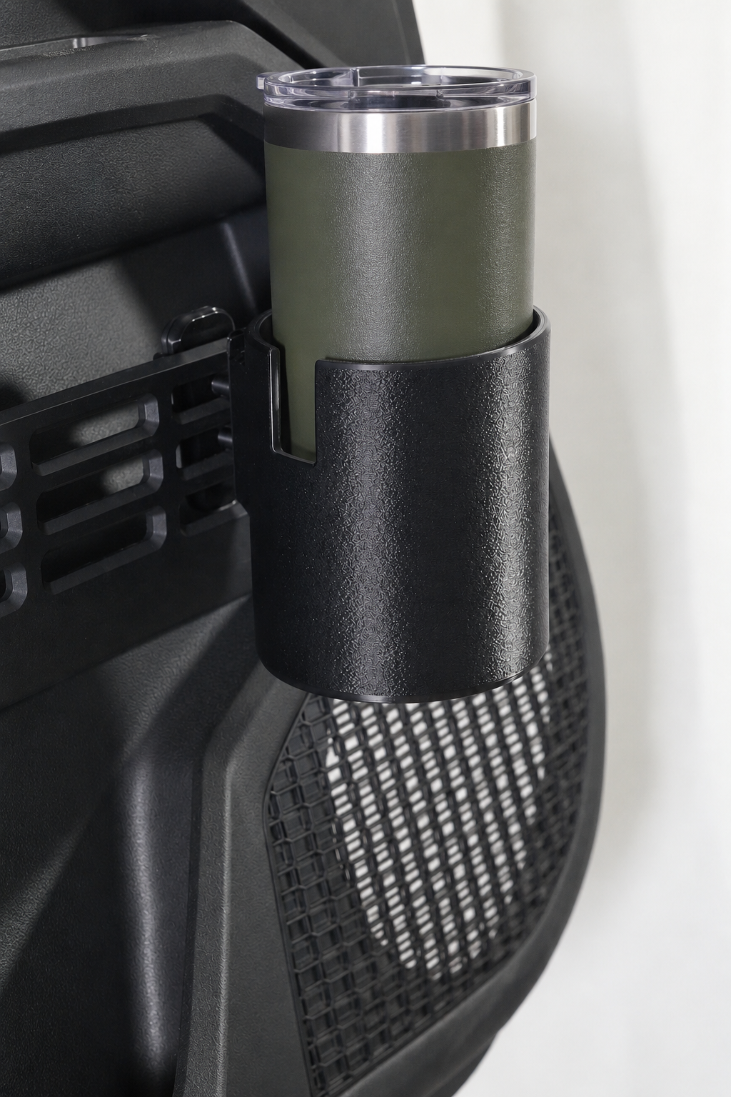 An olive green insulated travel tumbler with a clear lid, mounted in a black textured holder on a Toyota door panel.